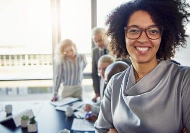 Young Businesswoman Smiling with Colleagues Working in the Backg